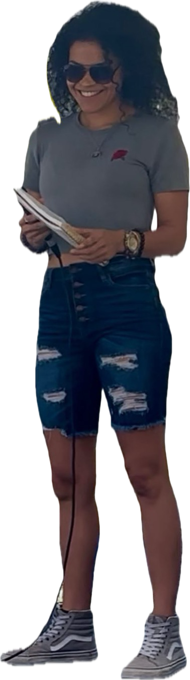 Cyndiii Deusa standing in sunglasses, notebook in hand, smiling.
